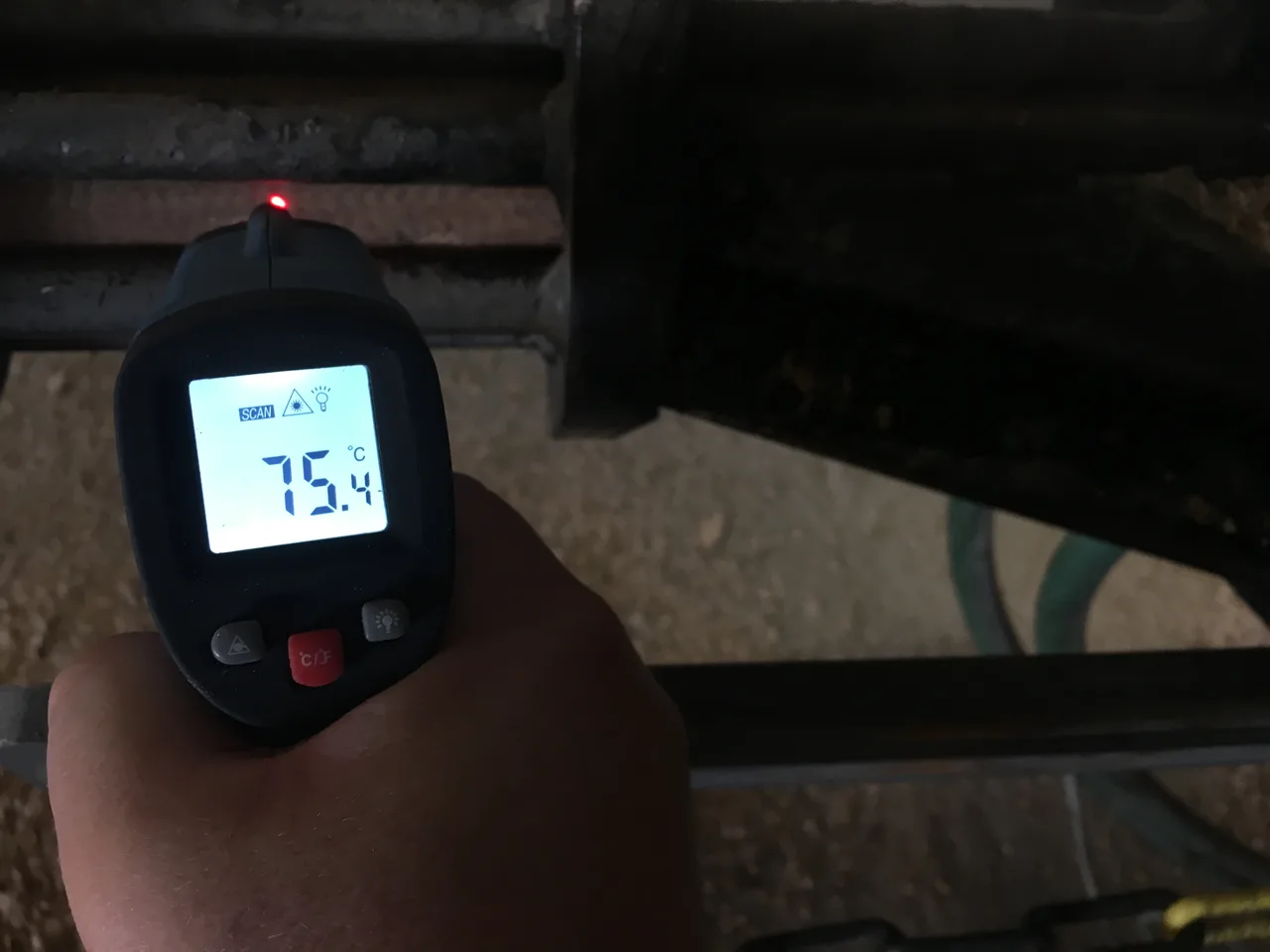 Infra hőmérő a gépből kilépő brikettszálra irányítva, a kijelzőn 75,4 °C